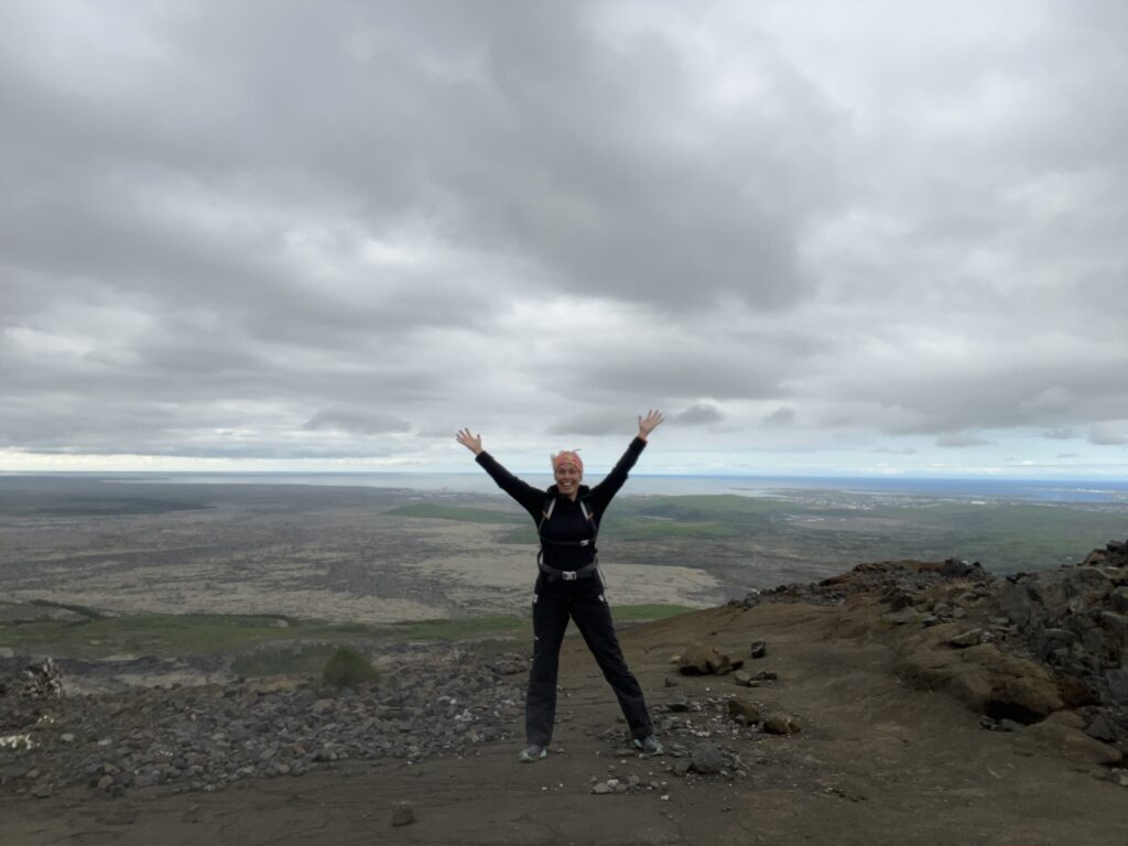 A figure spreads her arms in front of an Icelandic landscape